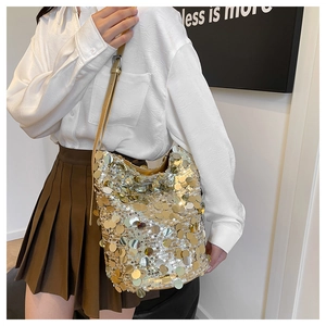 Dettaglio borsa a secchiello con paillettes dorate, dischi metallici e tracolla