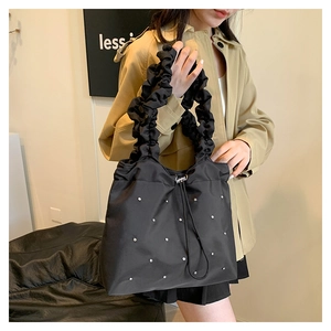 Detail of black pleated tote bag with silver studded accents and drawstring closure