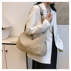 Detail of beige pleated nylon shoulder bag with wide strap and small metal logo