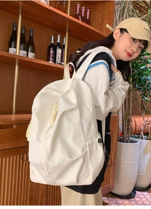White nylon backpack with vertical zipper pocket shown in a lifestyle indoor setting