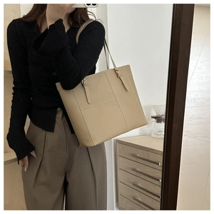 Détail d'un sac cabas beige en similicuir avec surpiqûres élégantes et boucles en métal