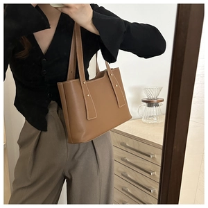 Detail of brown leather tote bag showing stitching and gold rivet on the shoulder strap