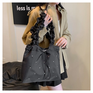 Detail of black pleated tote bag featuring drawstring closure and sparkling rhinestones