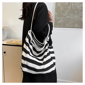 Detail of striped canvas tote bag with thick rope straps and black fabric knot accent