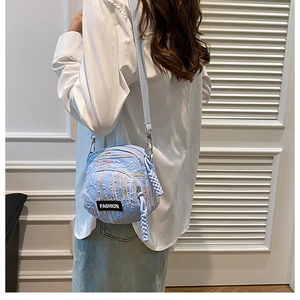Detail view of light blue canvas crossbody bag with textured fabric and fashion label