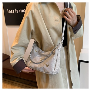 Detail of silver pleated crossbody bag with butterfly metal hardware and chain strap