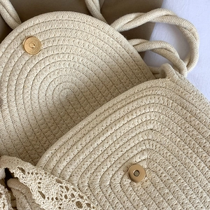 Beige woven straw shoulder bag with gold magnetic buckle and lace trim details