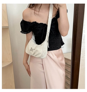 Mirror selfie showing the white pleated hobo bag with a metal butterfly on the shoulder