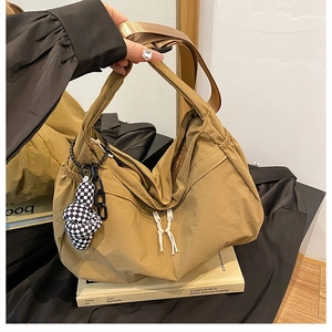 Détail du grand sac cabas kaki avec breloque en damier et accent de chaîne noire