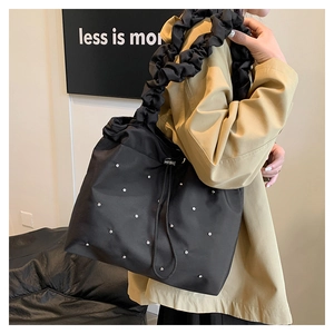 Close-up of black drawstring tote bag with ruffle strap and sparkling rhinestone detail