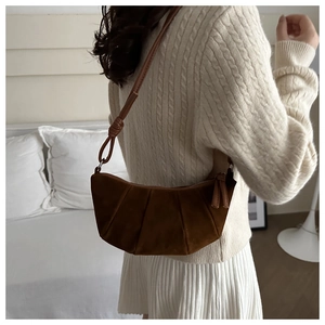 Detail of dark brown suede dumpling bag featuring vertical pleats and knotted shoulder strap