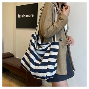 Detail of blue and white striped canvas tote bag with woven handles on model