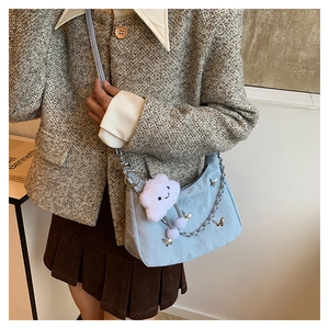 Light blue shoulder bag with butterfly prints and a white plush cloud charm on a model