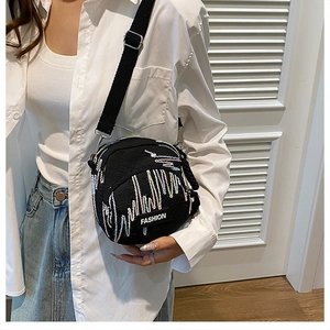 Close-up of black canvas crossbody phone bag with fashion label and wide strap on model
