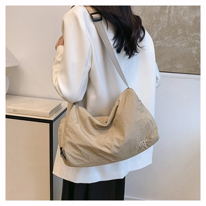 Detail of khaki nylon bag showing metallic FY logo and branded fashion zipper
