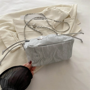 Silver pleated bucket bag with butterfly metal detail and chain strap on a blazer