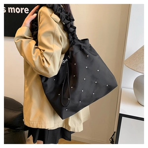 Detail of black tote bag with silver rivets and unique pleated scrunchie shoulder strap