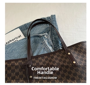 Macro detail of brown tote bag showing M-letter print and golden rivet accents