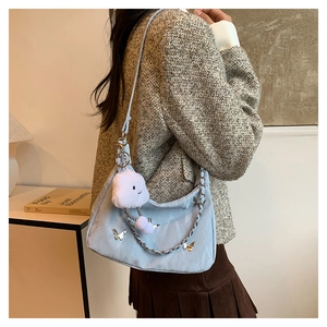 Detail of light blue shoulder bag with silver butterfly charm and plush cloud accessory