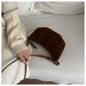 Detail of dark brown croissant bag showing soft suede texture and knotted shoulder strap