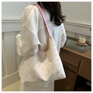 Détail de la texture tissée et de la bandoulière en cuir rose du sac porté épaule