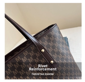 Macro shot of gold rivets and brown monogram pattern on stylish faux leather tote bag