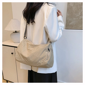 Close-up of beige crossbody bag with embroidered logo and nylon texture on model