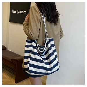 Close-up of blue and white striped canvas tote bag worn on shoulder by a model