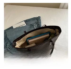 Top-down view of a spacious brown monogram tote bag holding a tablet and daily essentials