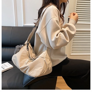 Détail du grand sac cabas beige avec poche latérale à cordon et pendentif damier