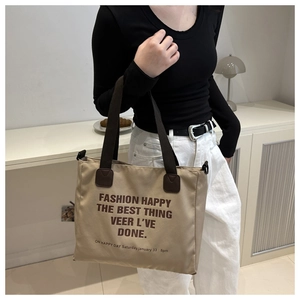 Detail of khaki canvas tote bag with brown straps and stylish oversized lettering print