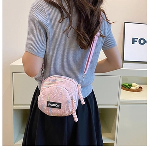 Detail of pink quilted nylon crossbody bag with fashion tag and colorful stitching