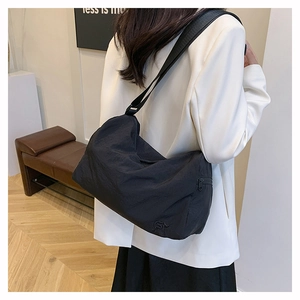 Detail of minimalist black crossbody bag with adjustable strap on a model outfit