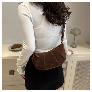Deep brown suede croissant bag shown on model highlighting its crescent shape and size