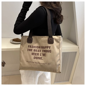 Détail d'un grand sac fourre-tout en toile kaki avec anses brunes et texte artistique