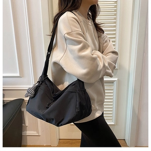 Détail du sac cabas en nylon noir avec cordons latéraux et charm nœud en damier
