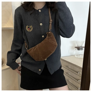 Brown suede croissant crossbody bag with pleated texture worn on model in cozy interior
