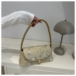 Detailed embroidery of pink flowers on a straw shoulder bag with a gold metal lock
