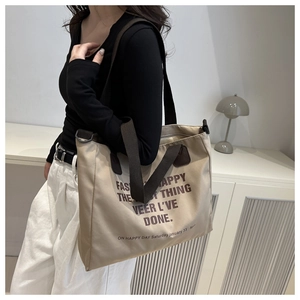 Detail of a large khaki canvas tote bag with brown straps and fashion print on the front
