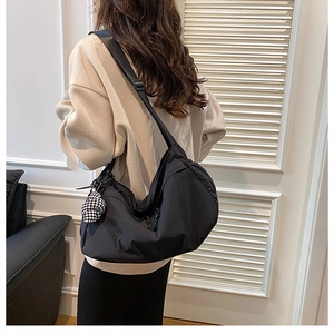 Détail du sac bandoulière croissant en nylon noir avec pendentif en damier et sangle