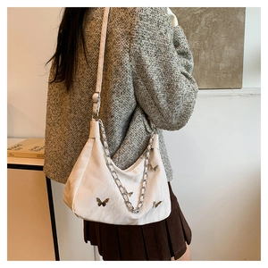 Detail of white hobo tote bag with silver chain and metal butterfly on female model