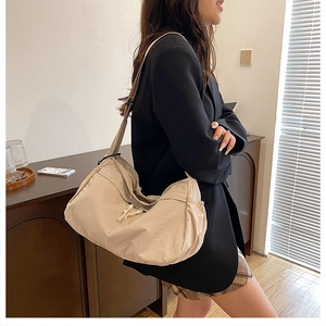 Grand sac cabas en nylon beige porté en bandoulière par un mannequin femme en blazer