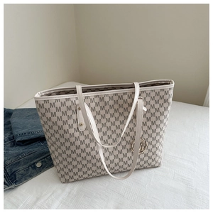 Detail of cream tote bag with grey M monogram pattern and gold metal charm pendant