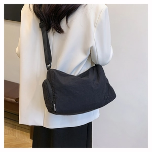 Detail of black nylon crossbody bag featuring fashion strap and embroidered logo accent