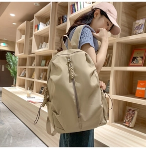 Detailed shot of a beige nylon backpack with woven zipper pulls in a cozy library setting