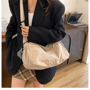 Détail d'un grand sac bandoulière beige en forme de ravioli avec pendentif coeur