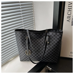 Detail of grey monogram tote bag with gold M-charm and black leather straps