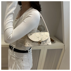 Detail of straw woven shoulder bag featuring delicate green floral lace embroidery