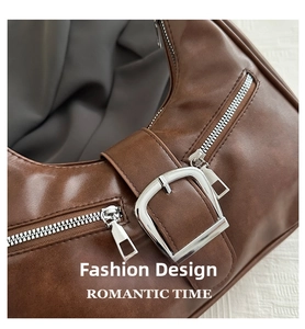 Close-up of brown leather bag with silver zippers and buckle strap detail