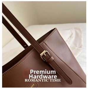 Detail of brown leather bag showing gold-plated buckle and romantic time engraving